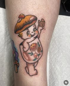 a person with a mushroom tattoo on their leg, holding a cookie in one hand