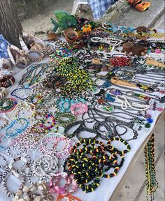 a table topped with lots of different types of bracelets and necklaces on display