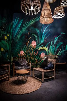 a room filled with lots of plants and lights hanging from the ceiling next to two wicker chairs