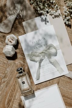 the wedding stationery is laid out on the table next to the perfume bottle and flowers