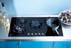 a black stove top sitting next to a bowl of fruit