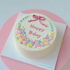 a decorated birthday cake on top of a pink and white plate with the words happy bday