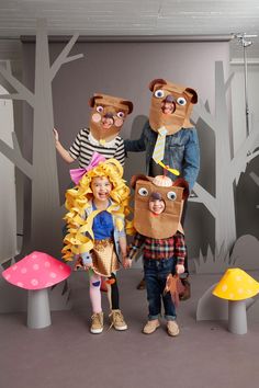 three people in costumes standing next to each other with mushrooms on the ground and trees behind them