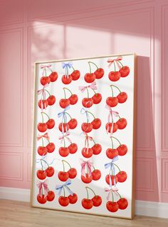 an art piece with cherries on it in front of a pink wall and wooden floor