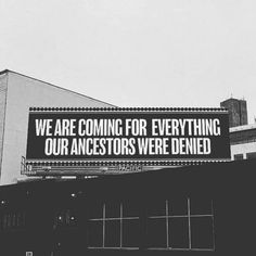 black and white photograph of an advertisement on the side of a building that says we are coming for everything our ancestors were identified