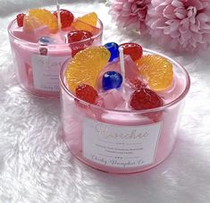 two small containers filled with fruit on top of a white blanket next to pink flowers