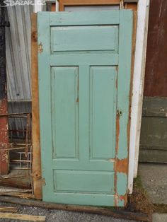 an old blue door sitting next to a pile of wood and other junk on the ground