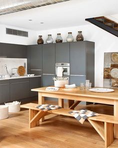 an open kitchen and dining area with wooden flooring, stainless steel appliances and gray cabinets