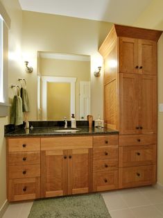 a large bathroom with wooden cabinets and marble counter tops, along with a green rug on the floor