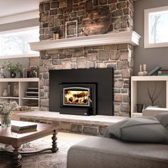 a living room filled with furniture and a fire place next to a stone wall mounted fireplace