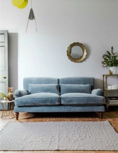 a blue couch sitting on top of a wooden floor in front of a white wall