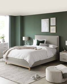 a bedroom with green walls, white furniture and a large bed in the middle of the room