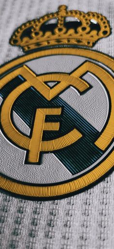 the real madrid crest is shown on a jersey with gold and black trimmings