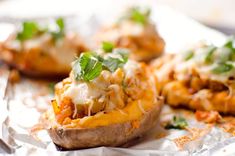 baked potato shells with cheese and herbs on foil wrapper, ready to be eaten