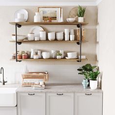 a kitchen filled with lots of white plates and bowls on top of wooden shelves next to a sink