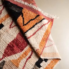 an orange, black, and white rug with fringes on the edges is folded up