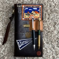 a notebook with a pen and some other items on top of it, sitting on the carpet