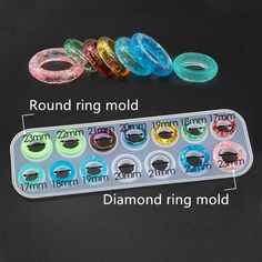 an assortment of different colored rings in a plastic container on a black surface with measurements for each ring