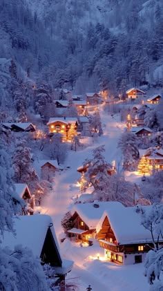 a snowy village is lit up with lights in the snow at night, surrounded by trees and mountains