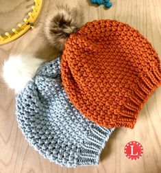 two knitted hats sitting on top of a wooden table