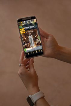 a person holding up a cell phone with a website on the screen in their hand