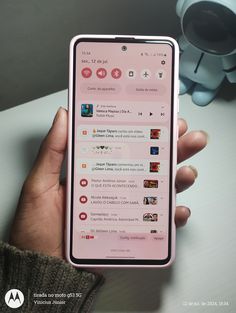 a person holding up a pink cell phone in their left hand, with social media on the screen