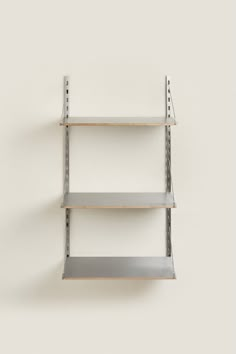 three metal shelving shelves on the wall with one empty shelf in front of them