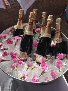 four bottles of champagne in ice with pink flowers