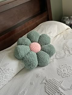 a crocheted flower pillow sitting on top of a bed with white linens