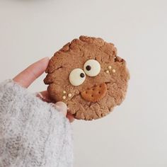 a cookie with googly eyes is being held by someone