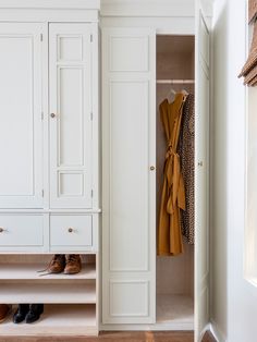 an open closet with shoes and coats hanging on it