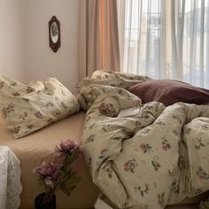 an unmade bed in a bedroom with floral comforter and pillows on top of it