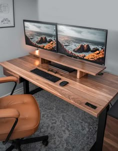 two computer monitors sitting on top of a wooden desk next to a brown leather chair