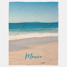 a towel with the word monica written in blue ink on top of an ocean beach