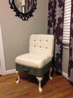 a green suitcase sitting on top of a hard wood floor next to a mirror and window