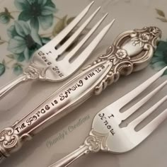 two silver forks with engraved words on them