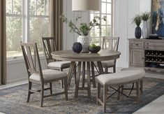 a dining room table with four chairs and a vase on top of it in front of a window