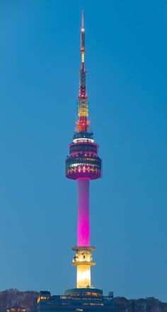 a very tall tower lit up in the night sky with lights on it's sides