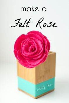 a pink rose sitting in a wooden box with the words make a felt rose on it