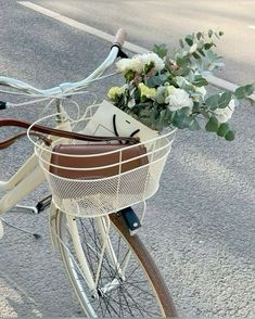 a bicycle with flowers in the basket parked on the side of the road next to an empty street