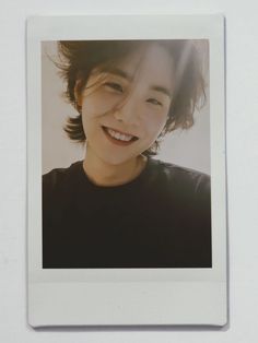 a polaroid photograph of a smiling young woman with dark hair and black t - shirt