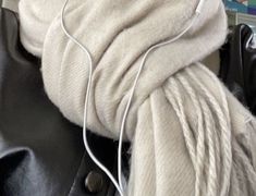 a pair of white ear buds sitting on top of a black leather bag next to some yarn