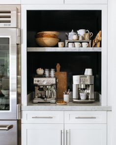 a kitchen with stainless steel appliances and white cupboards, including a coffee maker on the counter