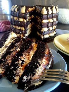 a piece of chocolate cake on a plate with a fork next to it and the rest of the cake in the background