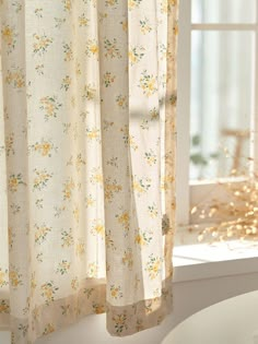 an open window with yellow flowers on it and white curtains in front of the window