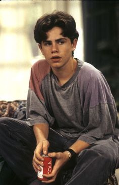 a young man sitting on the ground holding a can