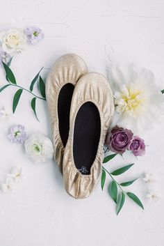 a pair of ballet shoes sitting on top of a white floor next to flowers and leaves