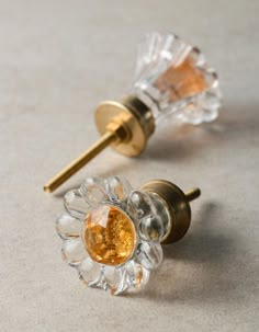 two clear glass knobs with a gold top and an orange flower on each one