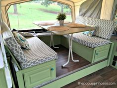 the inside of a camper with two beds and a table in front of it