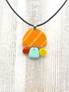 an orange, yellow and blue necklace with three circles hanging from it's cord